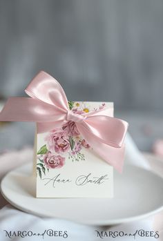 a white plate topped with a card and a pink ribbon tied around the top of it