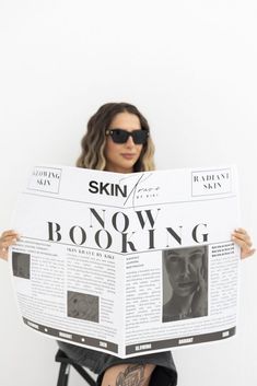 a woman sitting in a chair holding up a newspaper with the word skin on it