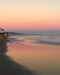 the sun is setting at the beach with palm trees in the background and water reflecting on the sand