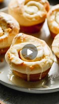 several baked goods sitting on a plate with icing drizzled around them