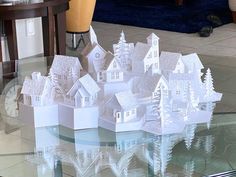 a glass table topped with white paper cut houses