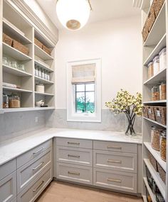 a white kitchen with lots of shelves and drawers on the wall, along with a vase filled with flowers