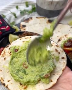 a hand holding a tortilla with guacamole on it