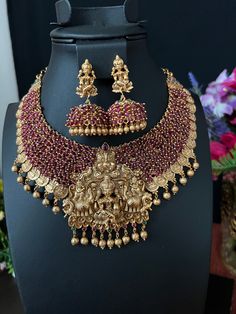 Goddess Lakshmi Bottu Pendent Grand Neckless with Earrings/ Temple Jewelry/ Antique gold finish / Cluster Maroon Beads / Indian Jewelry This is a grand Necklace set featuring Goddess Lakshmi surrounded by elephants and Maroon  beads and gold coins with Goddess Lakshmi form an impressive collar, while kemp stones add  DETAILS: Includes one necklace and two earrings. Necklace: Approx 9 inches. Adjustable length. Rope closure. Weighs 5.6 oz (159 g).  Earrings: 2 inch(es) long. Earring set weighs 1. Luxury Hallmarked Temple Jewelry Danglers, Gold Kundan Necklace With Dangling Beads For Diwali, Gold Chandbali Kundan Necklace With Dangling Beads, Gold Kundan Chandbali Necklace With Dangling Beads, Fusion Style Gold Jewelry Sets With Tilla, Festive Gold Kundan Necklace With Dangling Beads, Traditional Temple Necklace With Dangling Beads For Festive Occasions, Gold Kundan Bridal Necklace With Dangling Beads, Kundan Bridal Necklace With Gold Dangling Beads