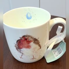 a coffee cup with a bird painted on the side and a tag attached to it