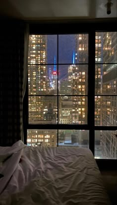 a bedroom with a view of the city at night