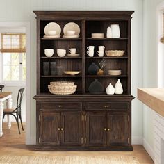 a large wooden cabinet with dishes on it in a room next to a dining table