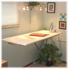 an ironing board sitting on top of a table next to a potted plant