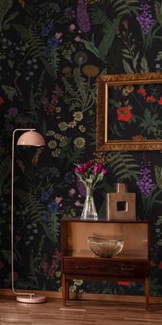 a vase with flowers is sitting on a table next to a lamp and framed photograph