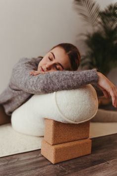 a woman laying on top of a pillow with her arms wrapped around the pillow that she is holding