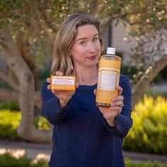 a woman holding two bottles of orange juice in one hand and an empty bottle in the other