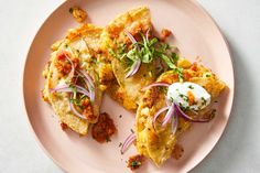 an omelet with onions and sour cream on top sits on a pink plate