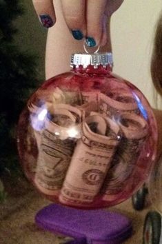 a person holding a glass ornament with money inside