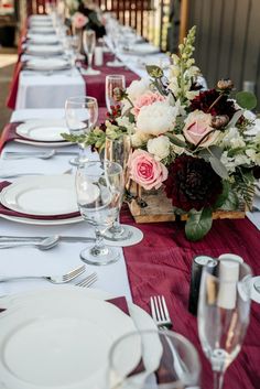 the table is set with white plates, silverware and flowers in a wooden crate