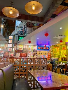 the inside of a restaurant with wooden tables and chairs, lights hanging from the ceiling