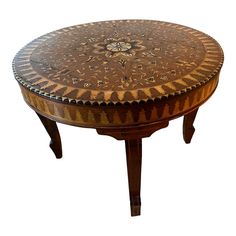 a round wooden table with an intricate design on it's top and two legs