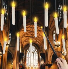 a person holding a wand in front of a church with candles hanging from the ceiling