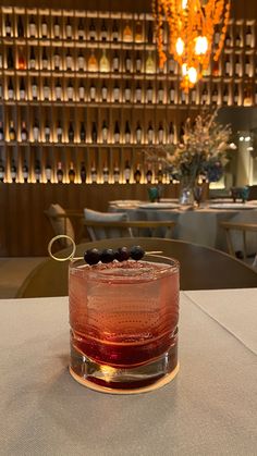 a close up of a drink on a table in a room with many bottles behind it