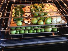 an oven with several trays of vegetables cooking in the oven, including green peppers and onions