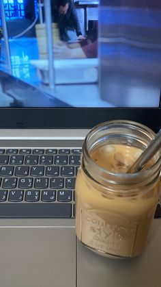 a jar of liquid sitting on top of a laptop computer next to a mouse and keyboard