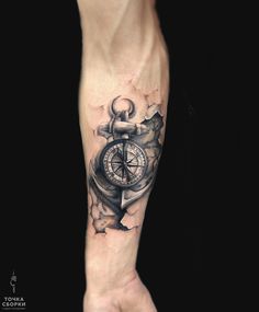 a man's arm with a compass and an anchor tattoo on the left forearm