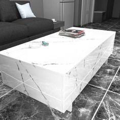 a white marble coffee table sitting on top of a floor next to a black couch