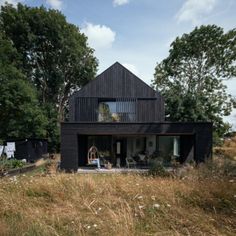 a black house sitting on top of a lush green field