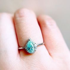 a woman's hand holding a ring with a large blue stone in the middle