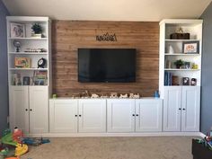 a living room with white cabinets and a flat screen tv mounted on the wall above it