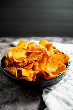 a black bowl filled with chips on top of a table