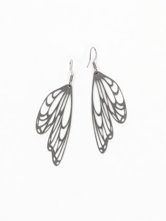 two pairs of silver earrings with wings on them, one in the shape of a butterfly