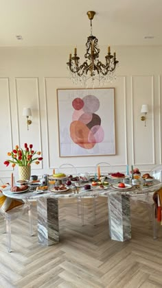 a dining room table is set up with food and flowers in vases on the side