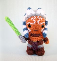 a small crocheted toy holding a green object in it's right hand