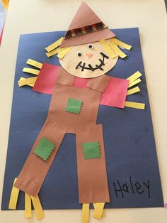 a scarecrow made out of construction paper on a blue background with the words happy written below it