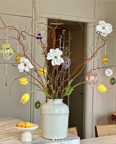 a vase filled with flowers sitting on top of a table next to a bowl of fruit