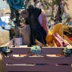 a wooden crate filled with lots of different types of clothing and accessories on top of a table