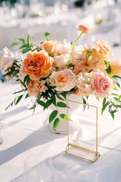 a vase filled with lots of flowers on top of a white tablecloth covered table