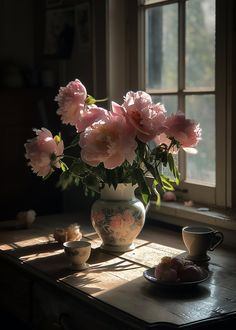 a vase filled with pink flowers sitting on top of a table next to a window