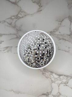 a white bowl filled with lots of black and white tiles on top of a marble counter