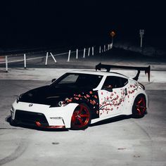 a white sports car with red flowers painted on it's side in the dark