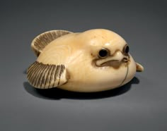 a ceramic figurine of a fish on a gray surface with black eyes and an open mouth