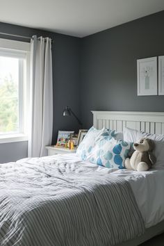 a white bed sitting under a window next to a stuffed animal on top of it