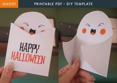 two hands holding halloween cards with ghost faces on them