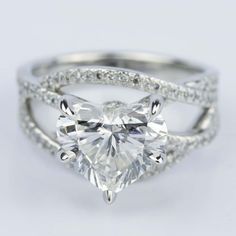 a heart shaped diamond engagement ring set with diamonds on the band and side stones in white gold