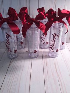 four coca - cola cups with red bows tied around them on a white wooden table