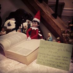 an open book sitting on top of a bed next to elf figurines