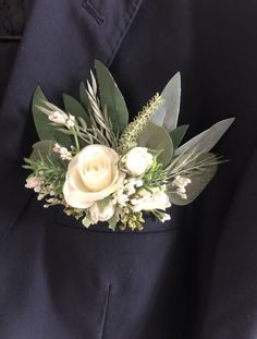 a boutonniere with white flowers and greenery on it's lapel