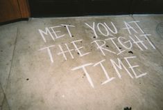 the words met you at the right time written in white chalk on an asphalt surface