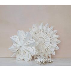 two white paper flowers sitting on top of a table