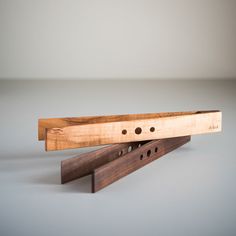 two pieces of wood sitting next to each other on top of a gray surface with holes in it